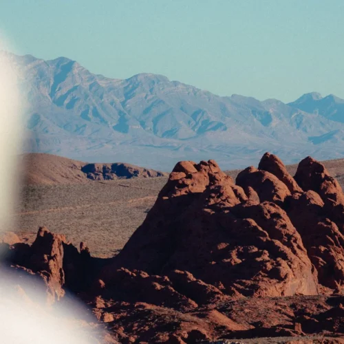 shopthietke com Desert landscape featuring reddish rocks distant mountains and a clear blue sky with some haze on the left side of the image